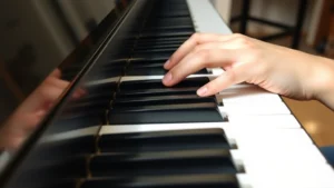 Close-up of pianist hands positioned on black and white piano keys, proper curved finger technique visible, natural studio lighting, acoustic piano