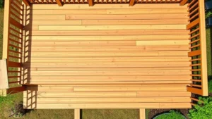 Overhead view of a completed pressure-treated wood deck with multiple levels, showing proper spacing between boards and clean finish, with landscaping visible around edges in daylight