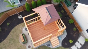 Aerial view of completed wooden fort structure with gabled roof, pressure-treated 4x4 posts, deck flooring, and surrounding landscaping in residential backyard setting