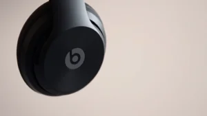 Close-up of Beats Solo 3 Wireless headphones showing power button and LED indicator light, professional studio lighting on neutral background